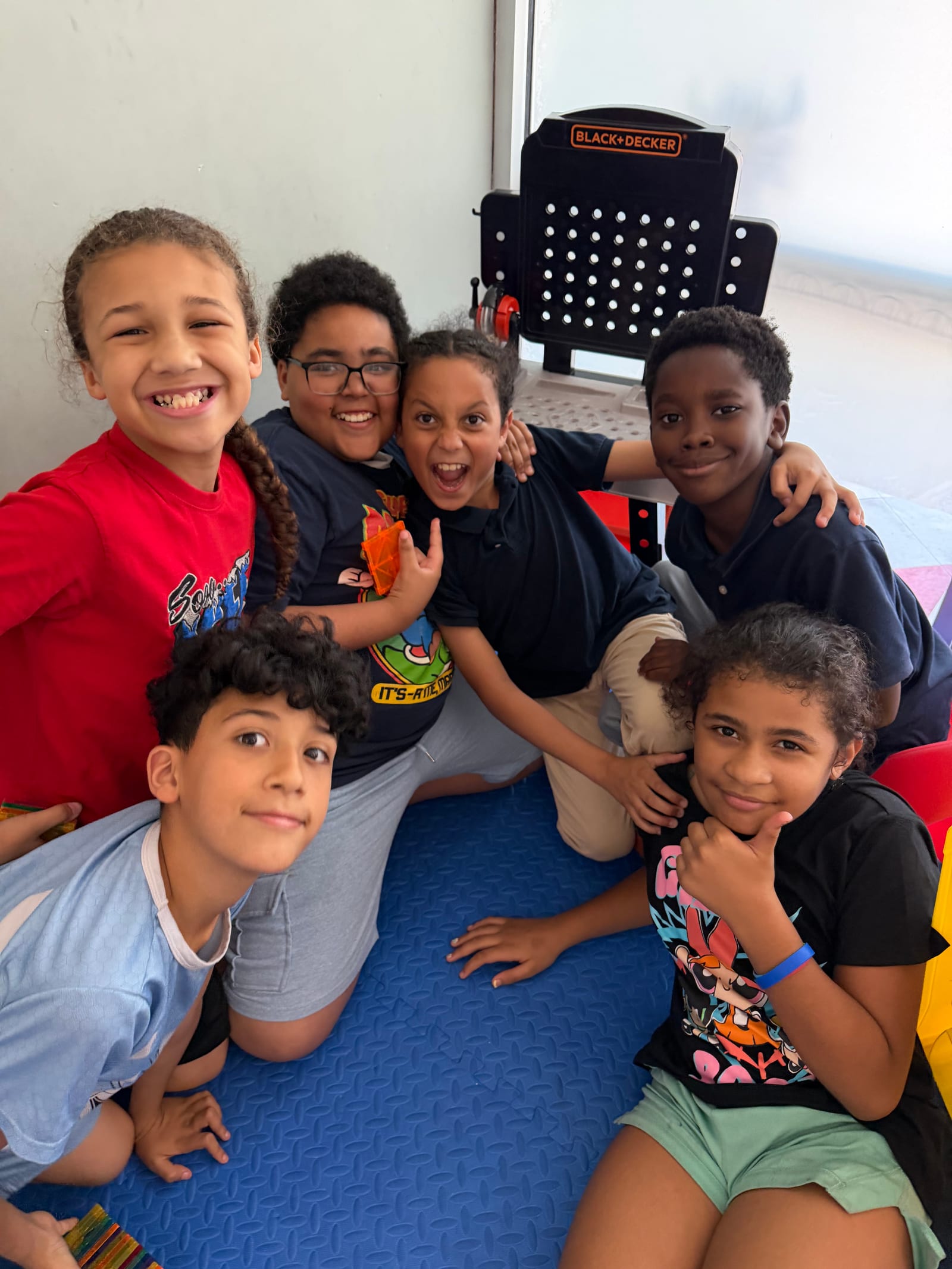 Six students piled together smiling for the camera